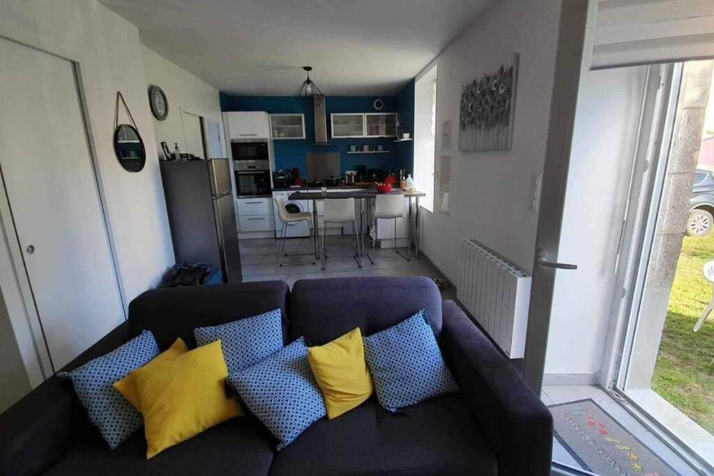 a couch with blue and yellow pillows in a living room at Studio entre Clohars Carnoet et Doelan in Clohars-Carnoët