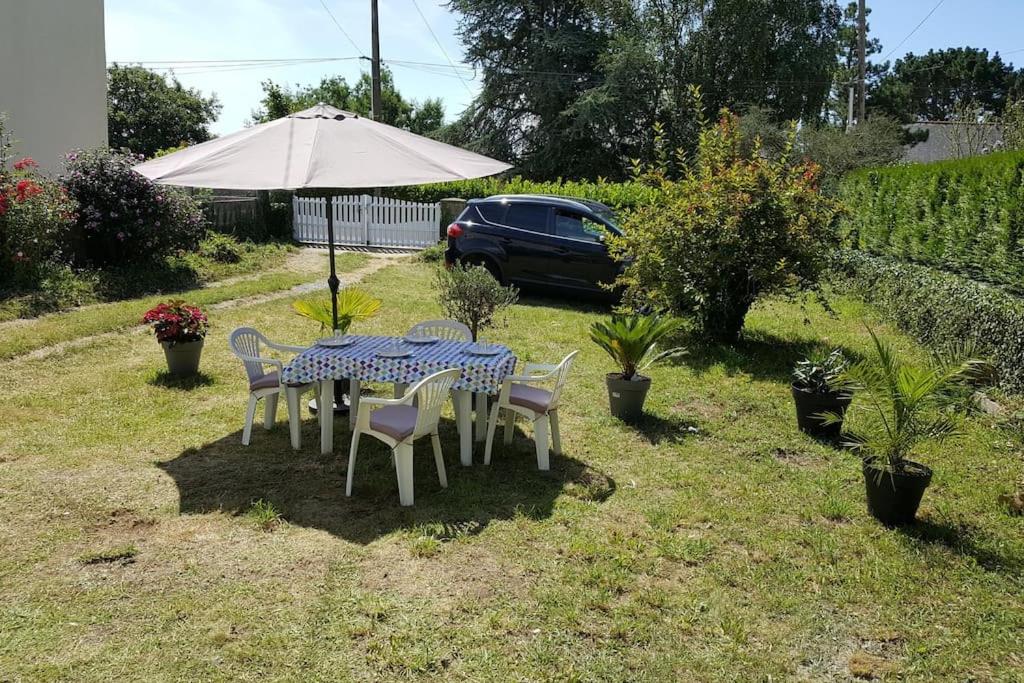 a table and chairs with an umbrella in a yard at Studio entre Clohars Carnoet et Doelan in Clohars-Carnoët