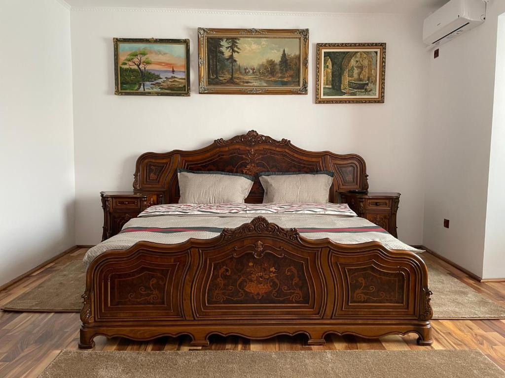 a bedroom with a wooden bed with paintings on the wall at M & I Apartment 3 in Târgu-Mureş