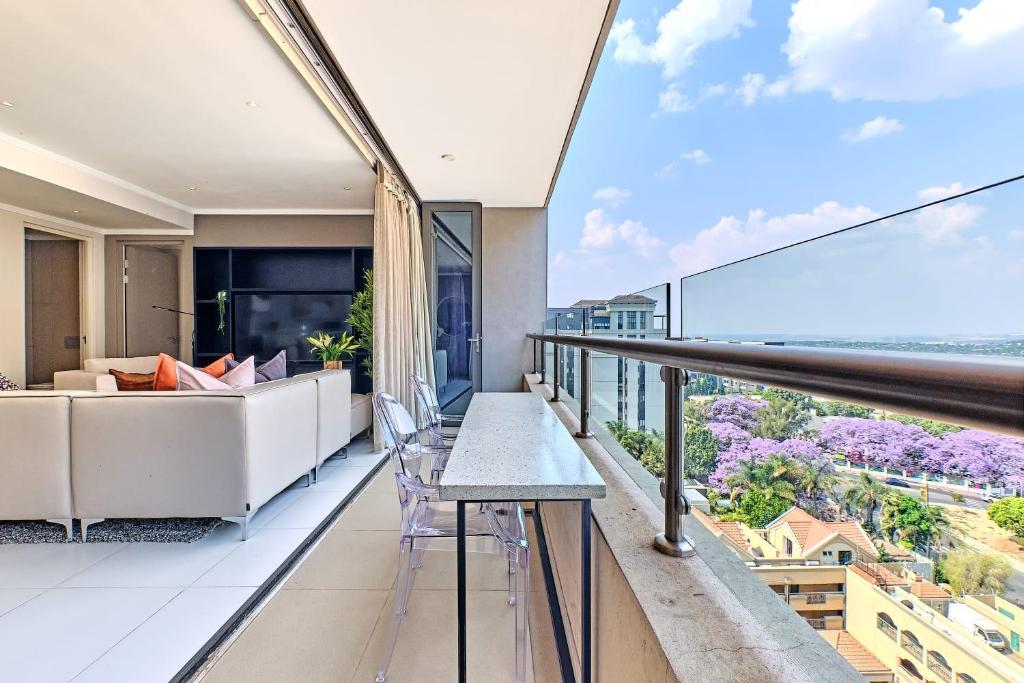 einen Balkon mit einem Sofa und einem Tisch in der Unterkunft La Vista Dream Apartments Luxury & Modern with City View and Inverter back up! in Johannesburg