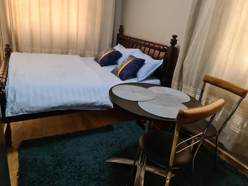 a bedroom with a bed and a table and chairs at Unia fancy flats - studio apartment two in Kampala