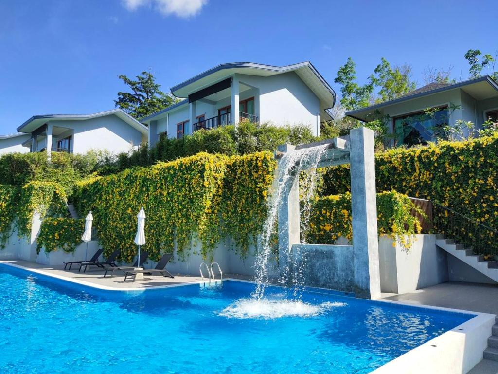 a swimming pool with a waterfall in front of a house at Khaolak Blue Sky Villa in Khao Lak