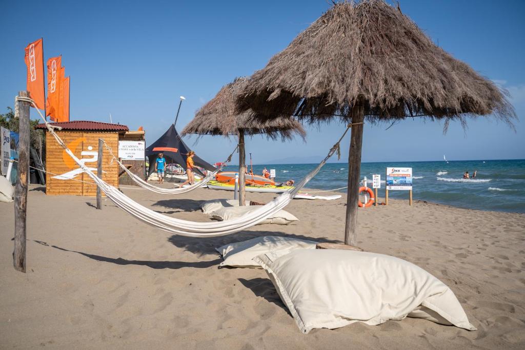 plaża z dwoma hamakami i słomianym parasolem w obiekcie Camping Maremma Sans Souci w mieście Castiglione della Pescaia