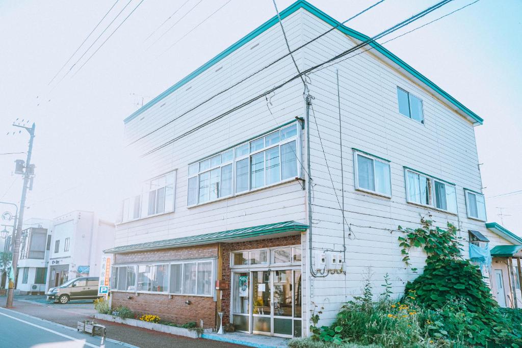 un bâtiment blanc sur le côté d'une rue dans l'établissement ゲストハウス＆カフェバー　エストアール, à Shibetsu