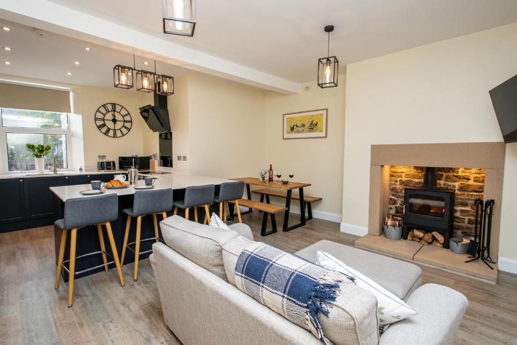 a living room with a kitchen and a fireplace at Burnside Cottage, Wark, Hexham in Hexham
