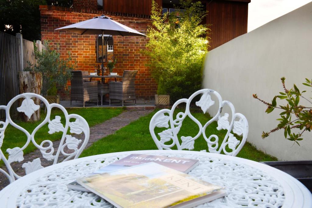 ein weißer Tisch und Stühle mit einem Buch darauf in der Unterkunft Fireman's Cottage in Canterbury