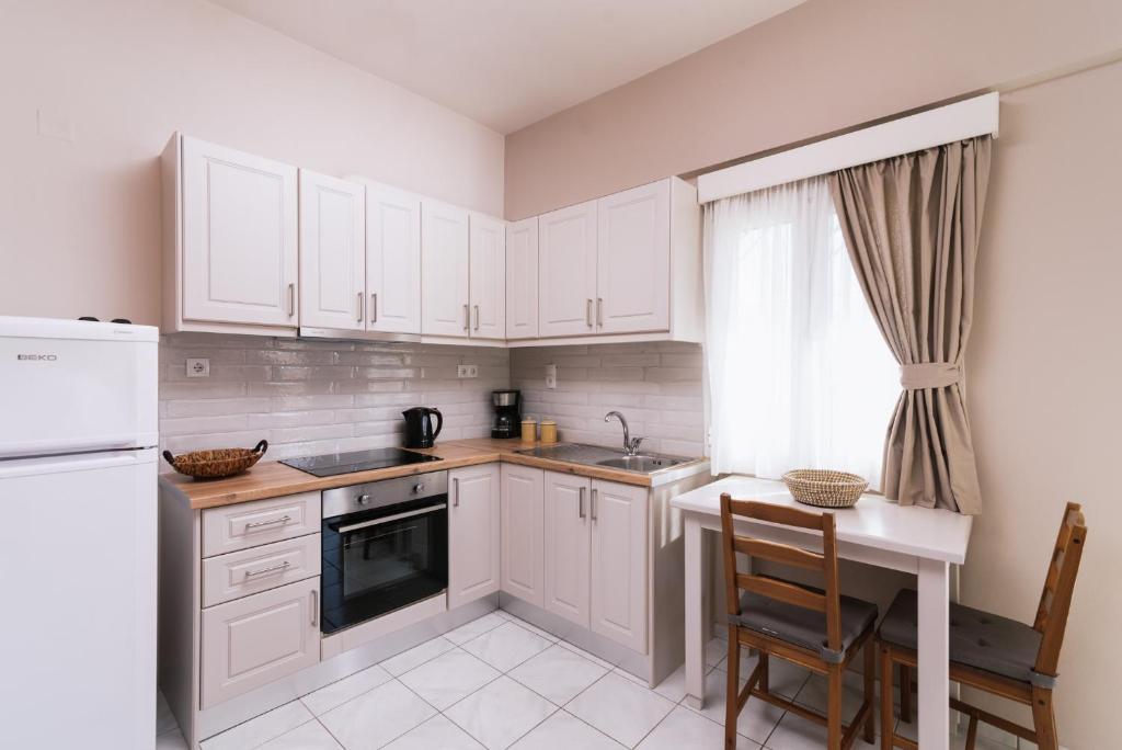 a kitchen with white cabinets and a table and a window at Filia Apartments in Pitsidia