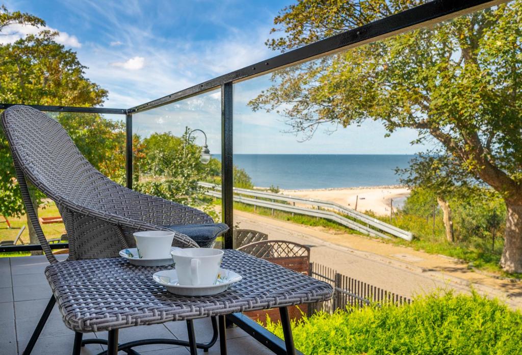 een tafel en stoelen op een balkon met uitzicht op het strand bij Apartament z widokiem na morze U Grażyny 2 in Jarosławiec