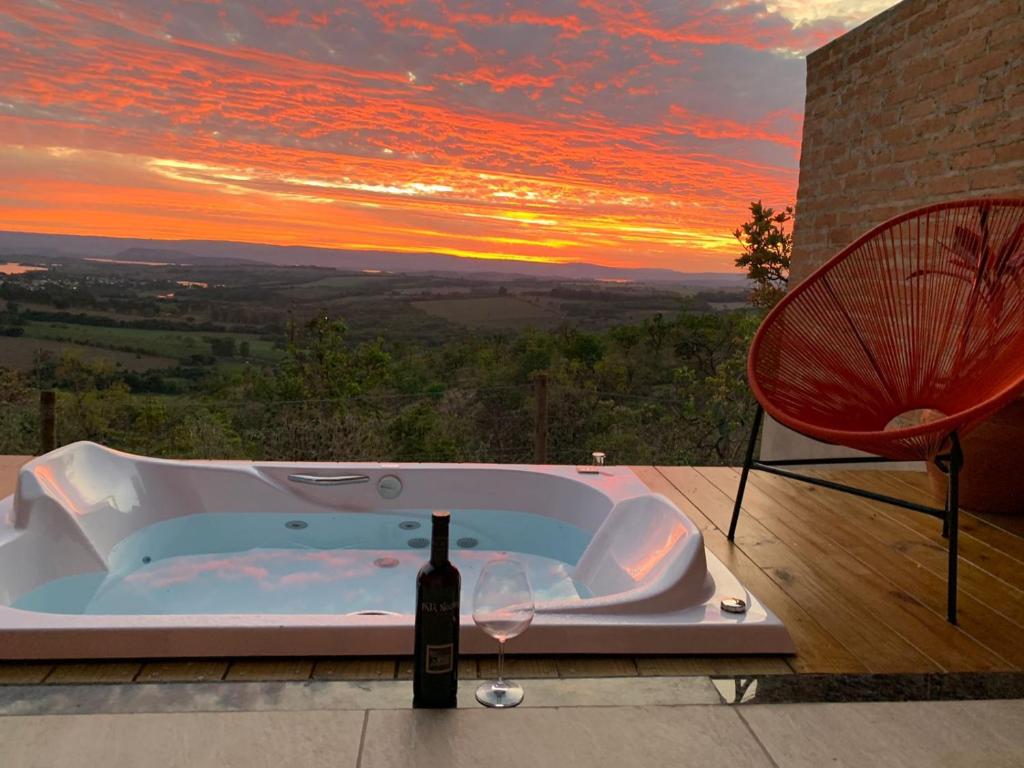 a hot tub with a bottle of wine next to a chair at Casa Erva Doce Pousada in Delfinópolis
