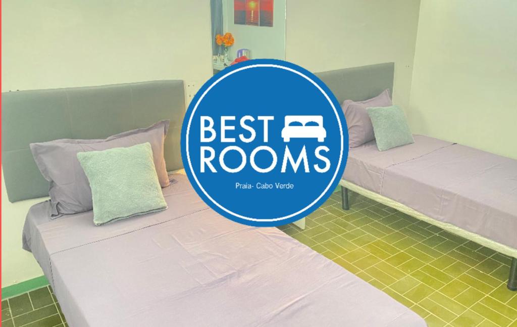 a blue best rooms sign in a room with two beds at Best Rooms- Quarto 2 Plateau in Praia