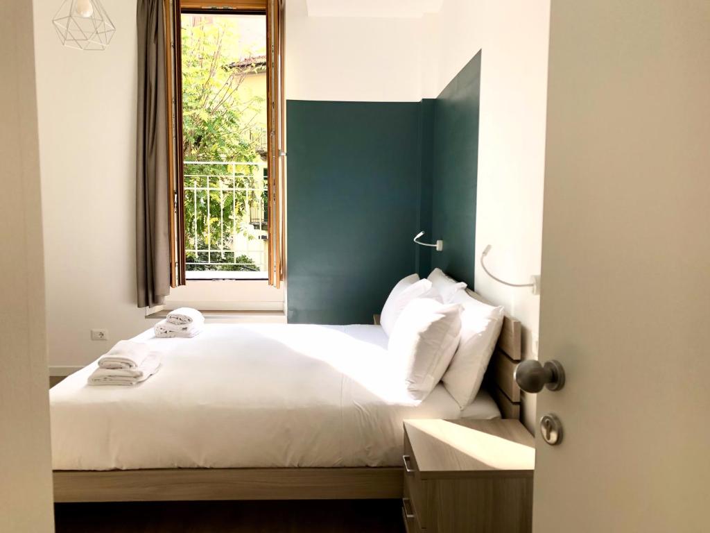 um quarto com uma cama com uma cabeceira verde e uma janela em RELSTAY - Amendola em Milão