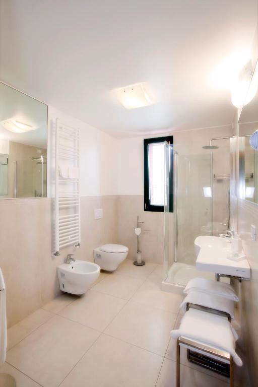 a white bathroom with two sinks and two toilets at Hotel Marco Polo in Lido di Jesolo