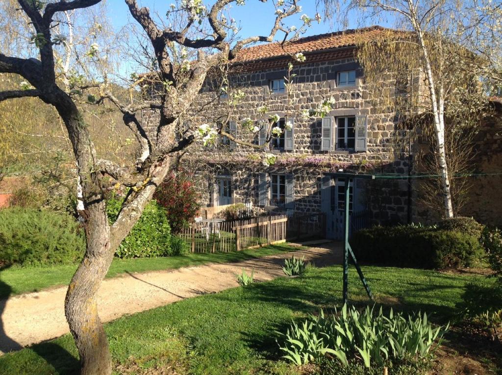 una casa de piedra con un árbol delante en Les Jardins d'Anna - Chambres d'hôtes, en Tapon