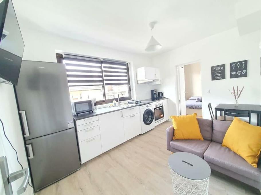 uma cozinha e sala de estar com um sofá e um frigorífico em L'Orchidée - Cosy Flat, 20min From Paris em Drancy