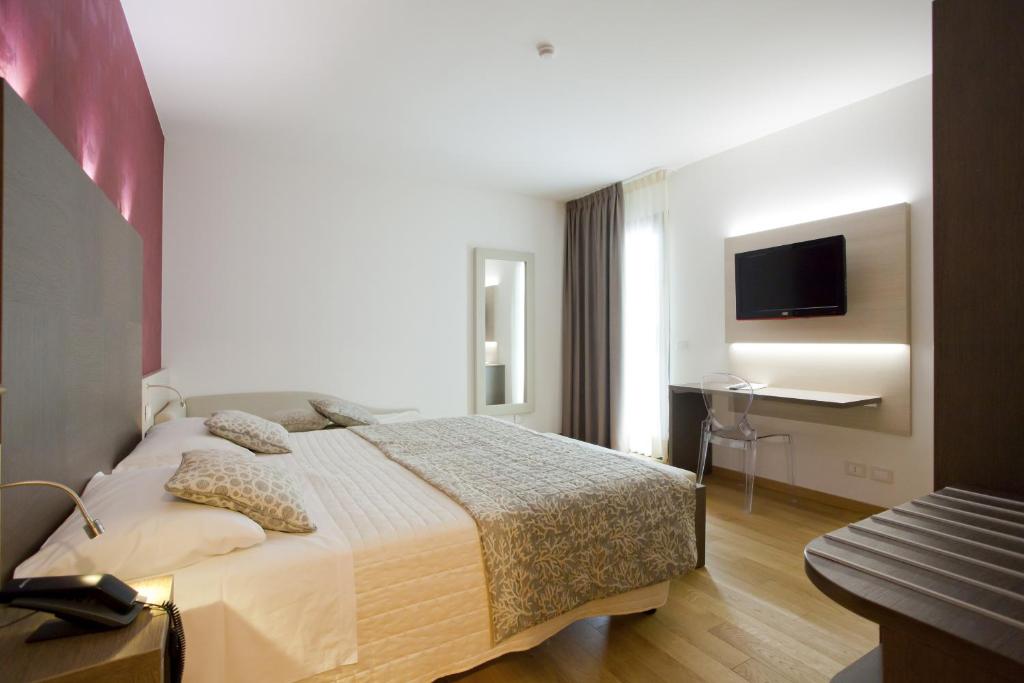 a bedroom with a bed and a desk and a television at Hotel Marco Polo in Lido di Jesolo