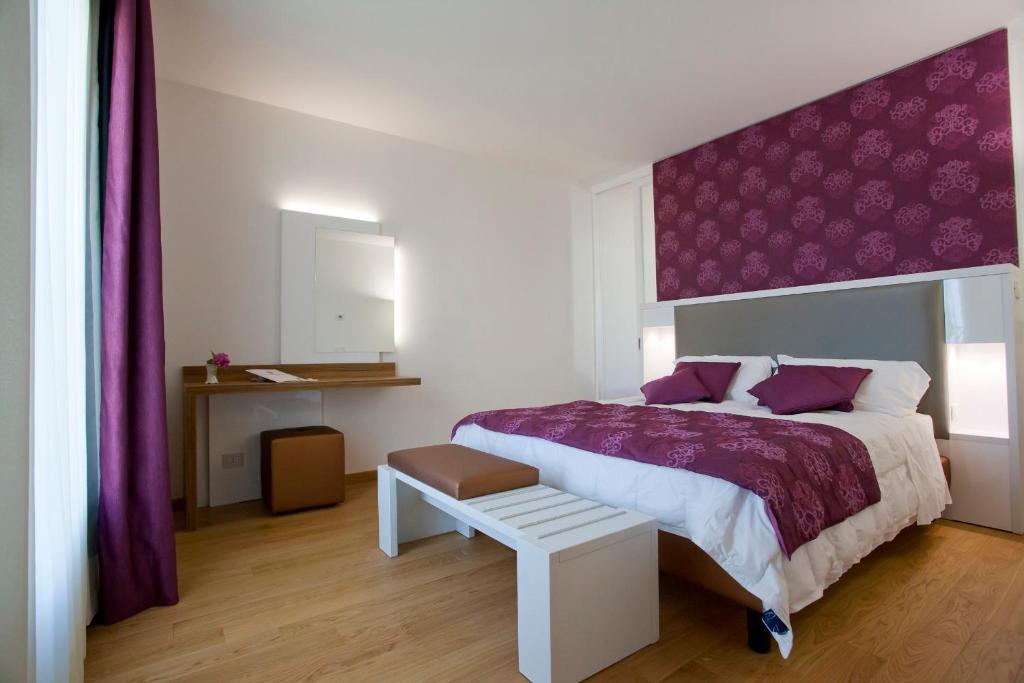 a bedroom with a large bed with a purple headboard at Hotel Marco Polo in Lido di Jesolo
