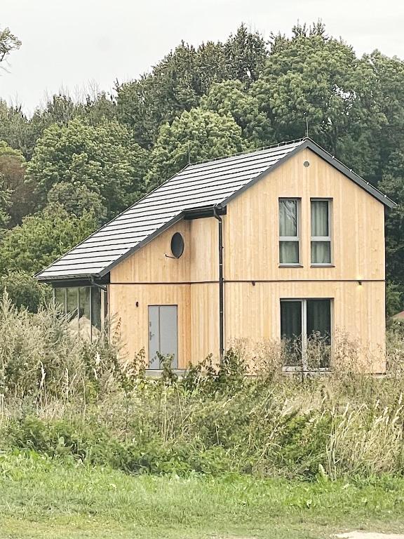 a wooden house with a black roof in a field at Bieleniówka in Nakielno