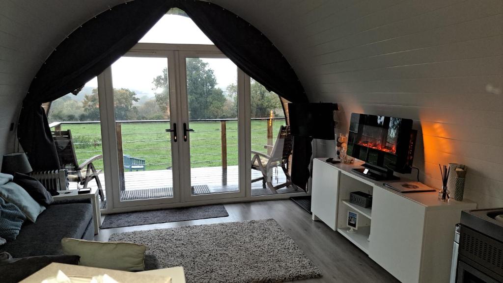 a living room with a large window and a tv at The Pod - Luxury Glamping Holiday Lodge in Arley