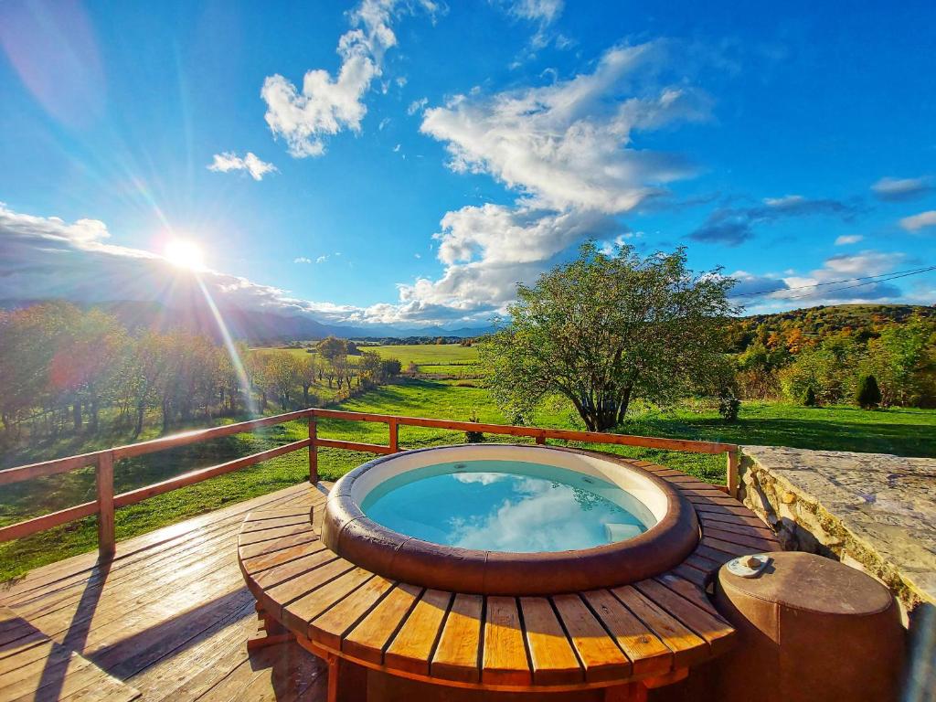 una bañera de hidromasaje en una terraza con el sol en el cielo en Peter's Pine Cottage, en Korenica