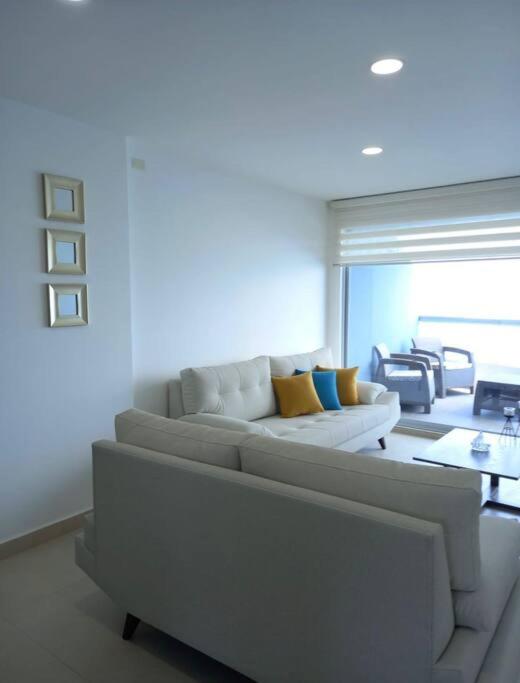 una sala de estar con un sofá blanco con almohadas amarillas en Edif. Deymar - Departamento frente al mar 9no piso, en Tonsupa