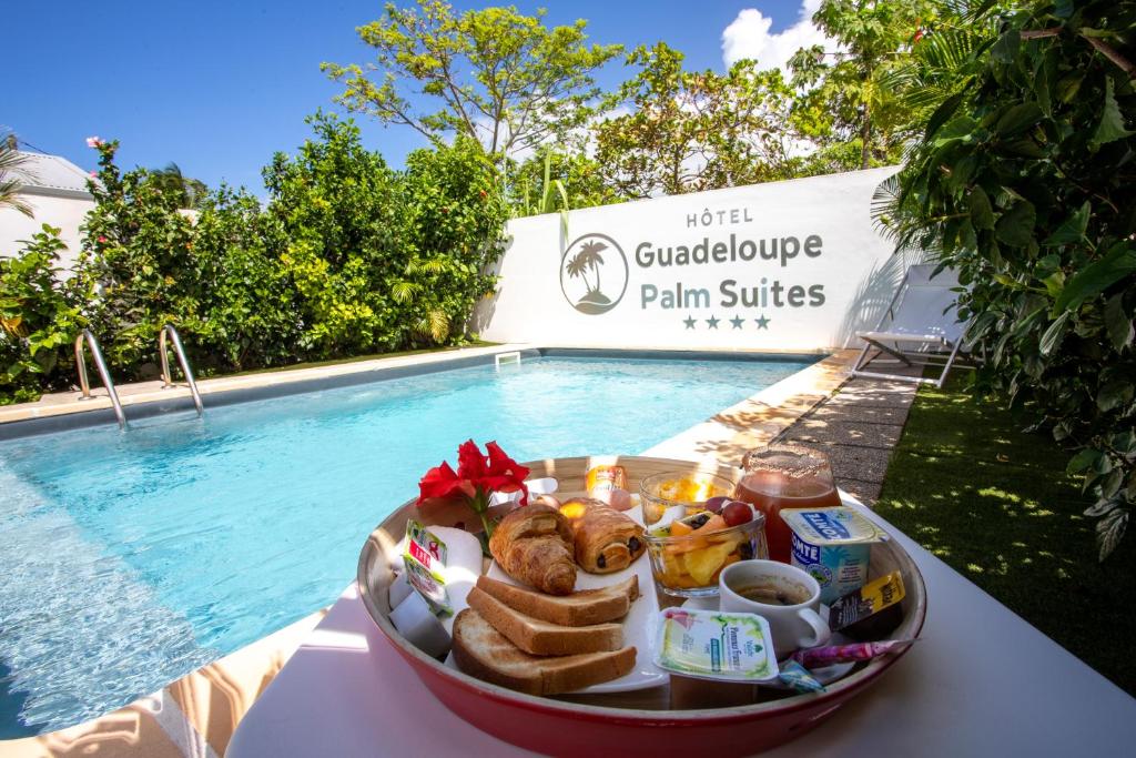 Hôtel Guadeloupe Palm Suites في سانت فرانسوا: صينية طعام على طاولة بجوار حمام سباحة