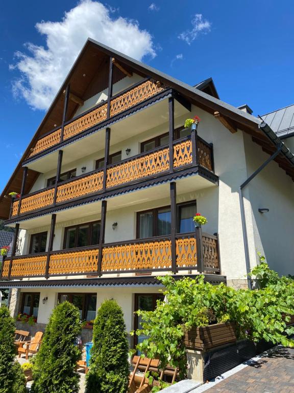 a building with wooden balconies and tables and chairs at Willa Aurinia in Szczawnica