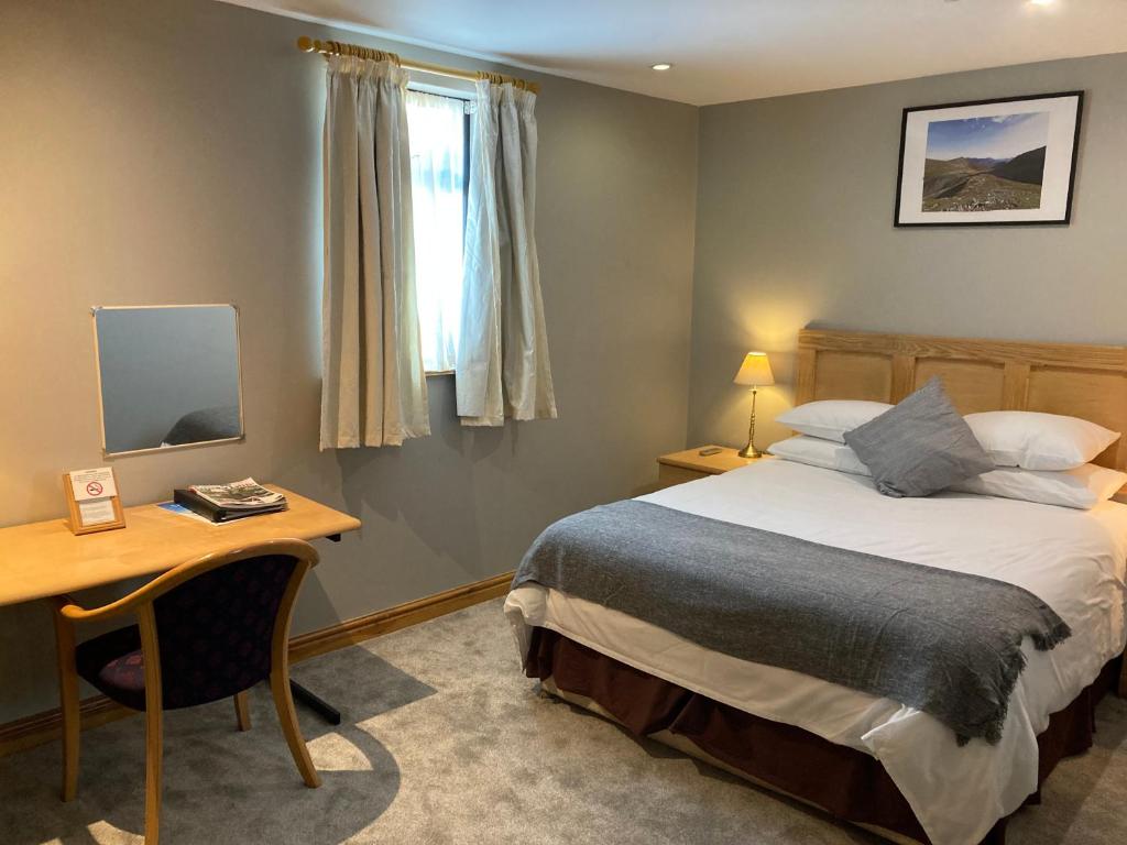 a bedroom with a bed and a desk and a window at The Sleepwell Inn in Workington