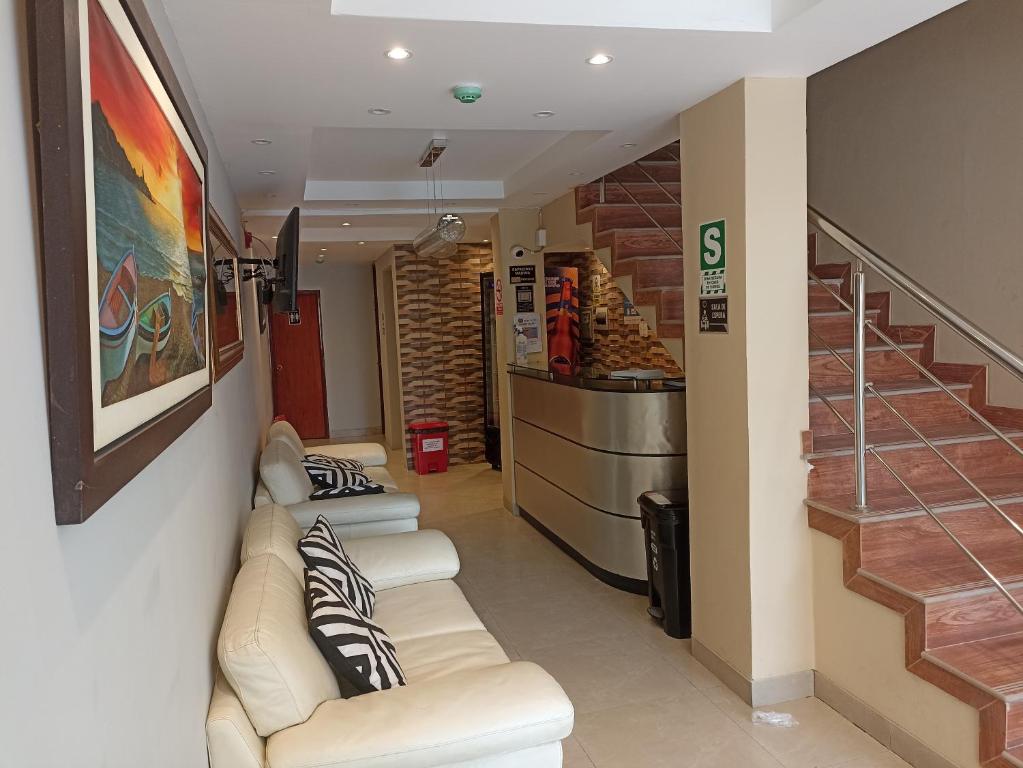 una sala de espera con 2 sofás blancos y una escalera en HOTEL ALFONSO UGARTE, en Chiclayo