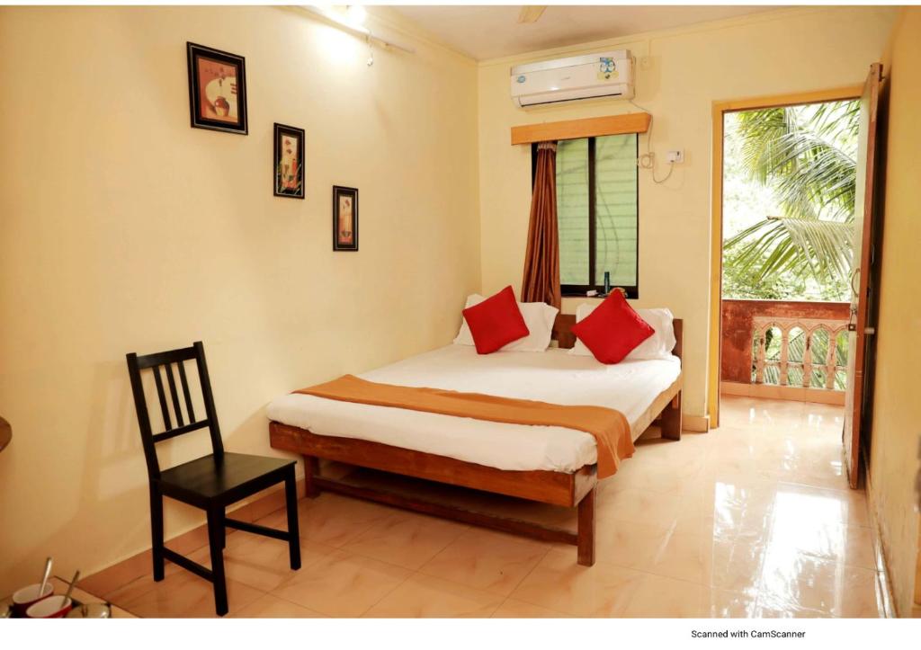 um quarto com uma cama com almofadas vermelhas e uma cadeira em Nisarg Resort em Guhagar