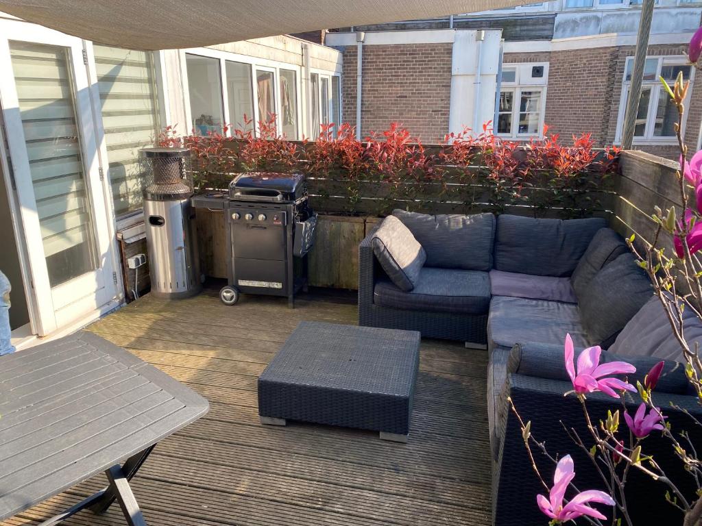 a patio with a couch and a table and a grill at Rooftop Terrace Apartment in Amsterdam