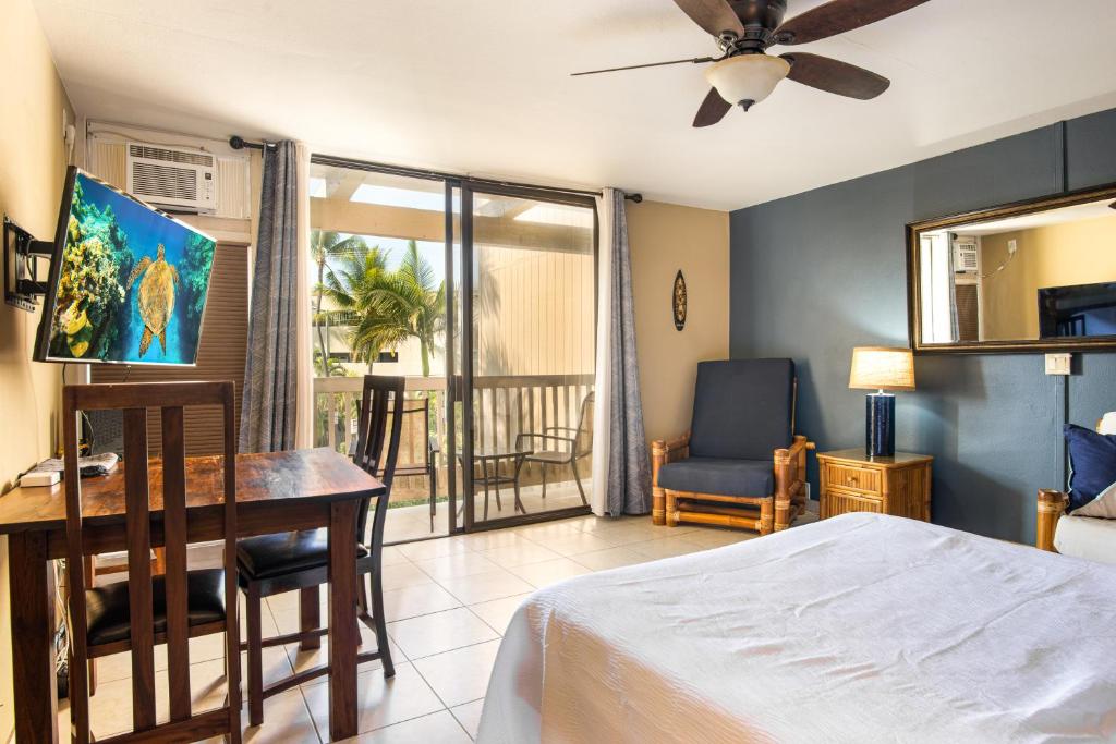 1 dormitorio con cama, escritorio y balcón en Kona Bali Kai Resort #234, en Kailua-Kona