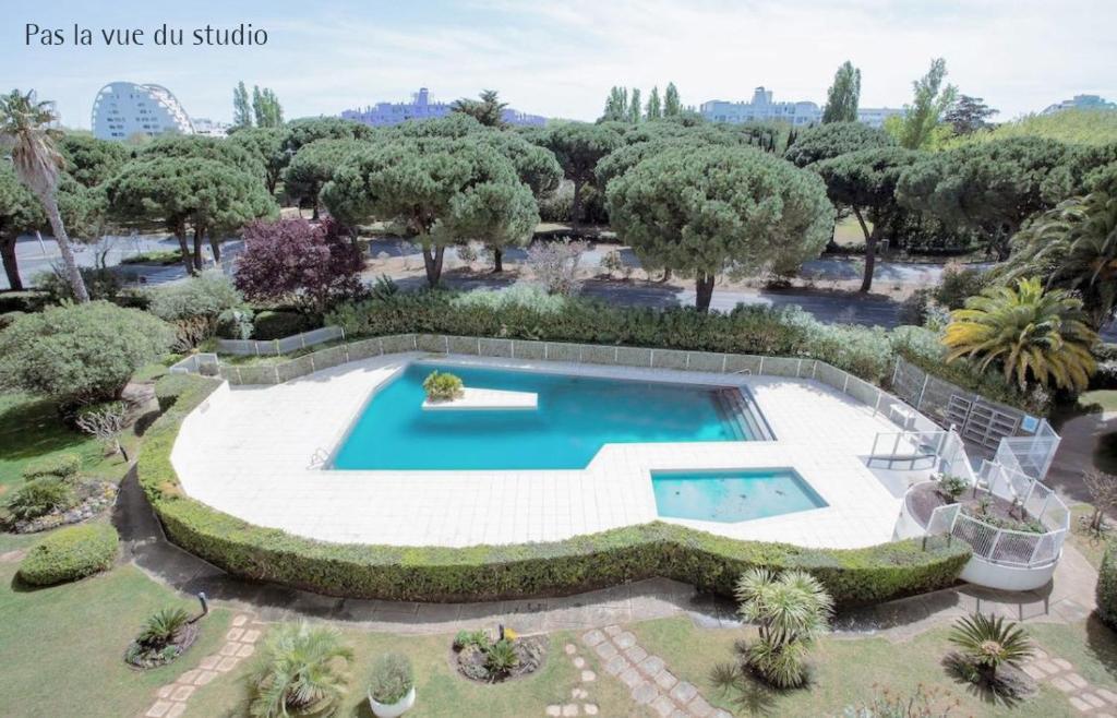 - une vue sur la piscine dans le jardin dans l'établissement Blue Sky La Grande Motte Studio -Pool-5min Beach -Queensizebed -WiFi, à La Grande Motte