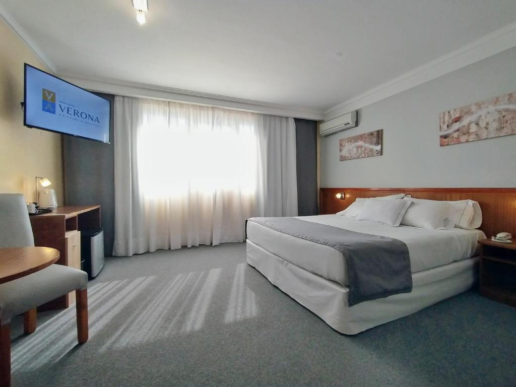 a hotel room with a large bed and a television at Gran Hotel Verona in Mar de Ajó