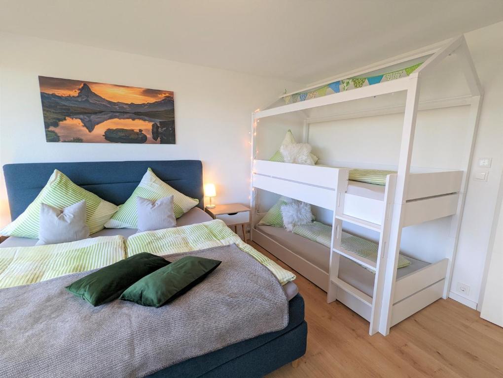 una camera con 2 letti a castello e un letto con una scala. di Ferienwohnung BergOase a Scheidegg
