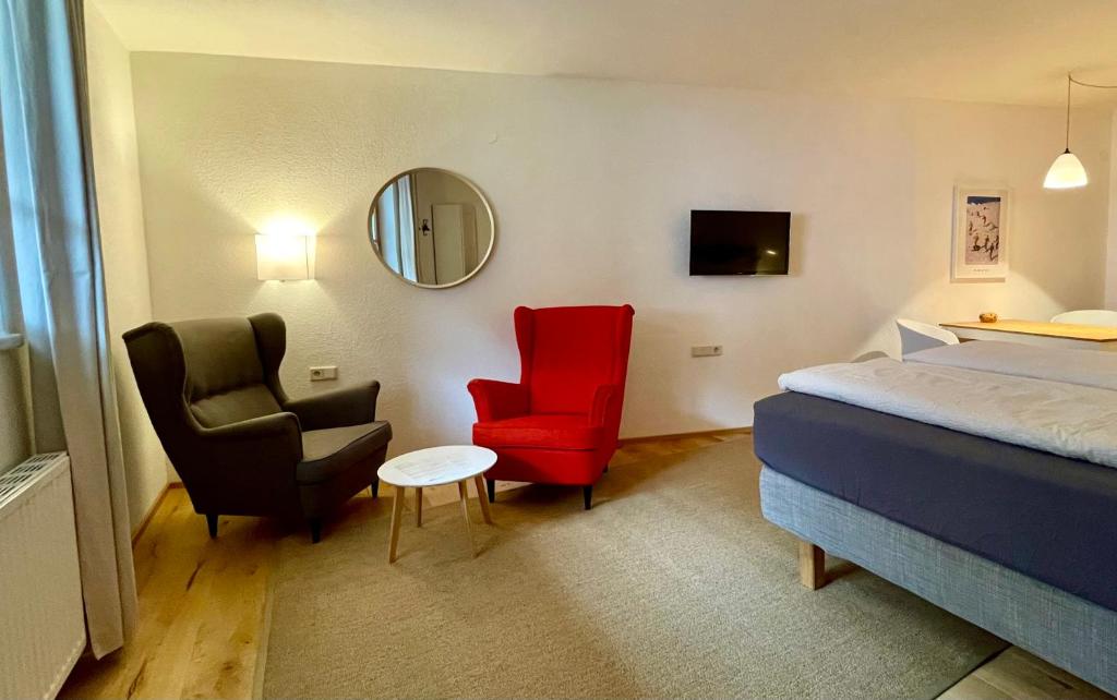 um quarto de hotel com uma cama e duas cadeiras e um espelho em Schönes Studio im ruhigen Kaunertal em Kaunertal