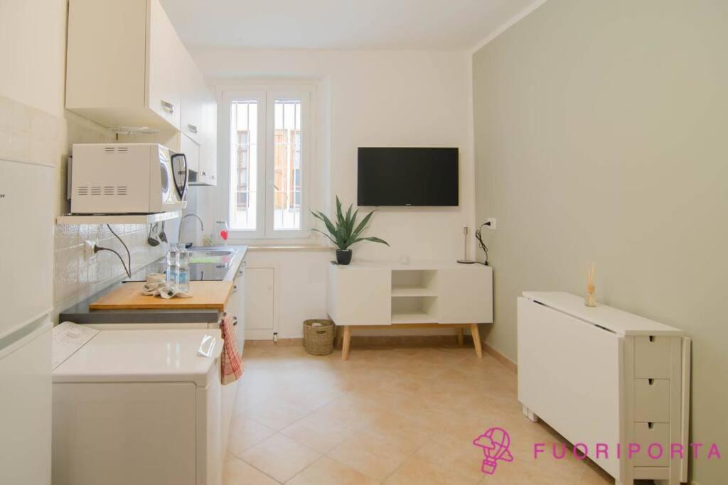 a white kitchen with a sink and a microwave at Borgo Cocconi 33 in Parma