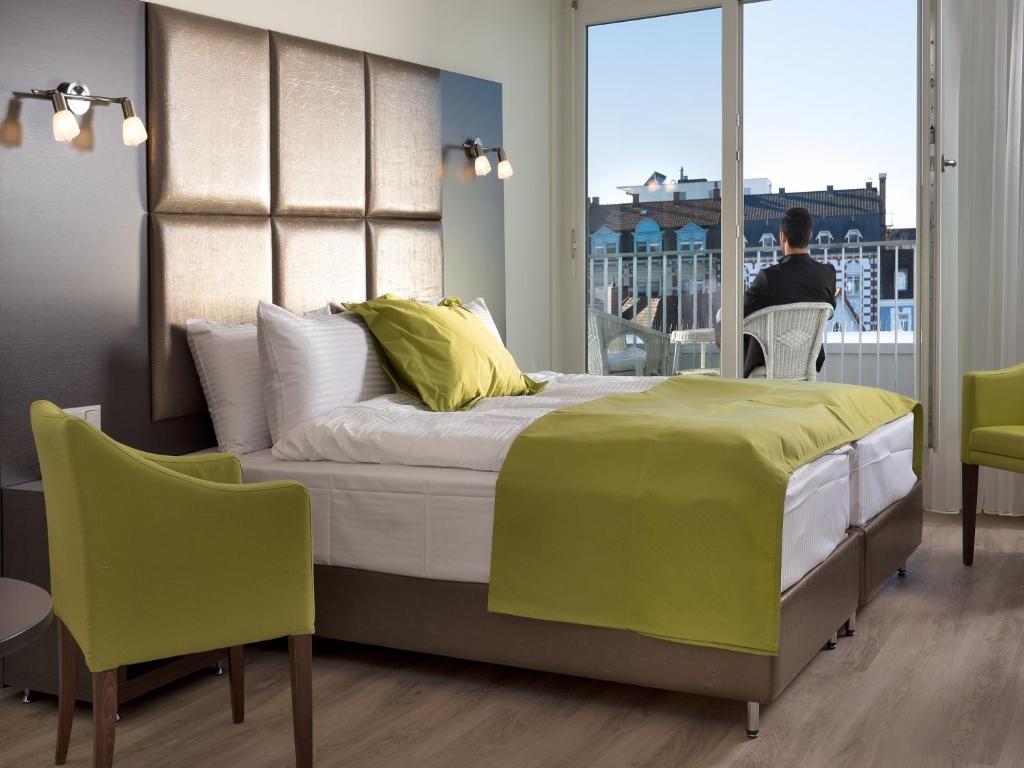 ein Schlafzimmer mit einem Bett und eine Person auf einem Stuhl in der Unterkunft Boutique Hotel Bellevue Rheinfelden / Basel in Rheinfelden