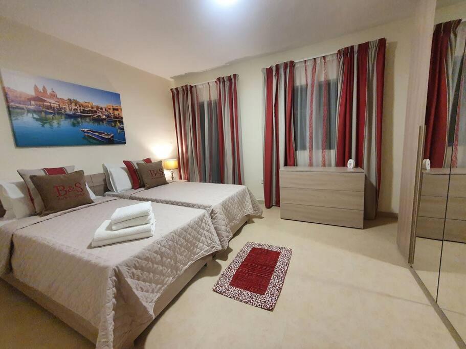 een hotelkamer met 2 bedden en 2 ramen bij B&S Accommodation Solitary Duplex Maisonette in Żejtun