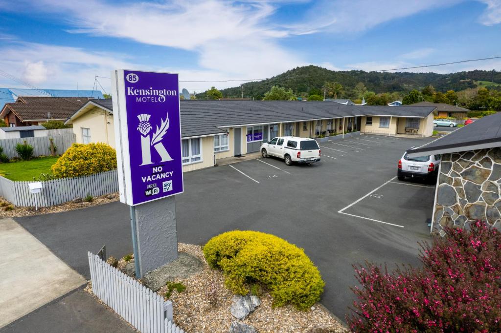 a parking lot with a purple sign in front of a motel at Kensington Motel in Whangarei