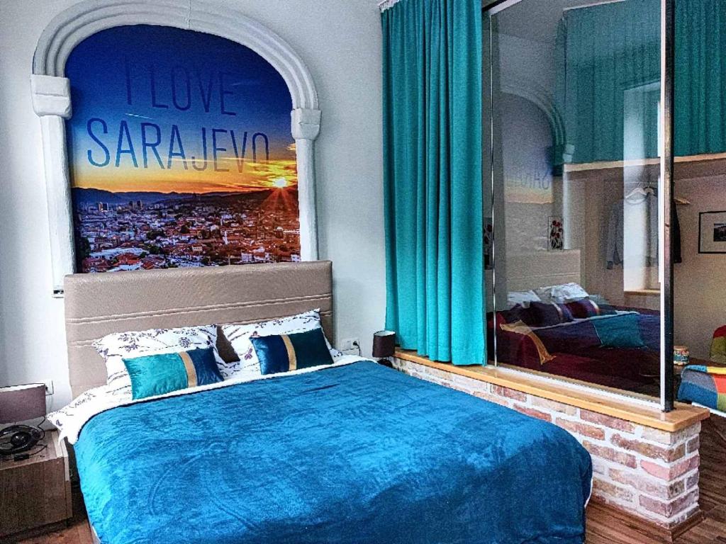 - une chambre avec un lit bleu et une grande fenêtre dans l'établissement KIZZ Apartment, à Sarajevo