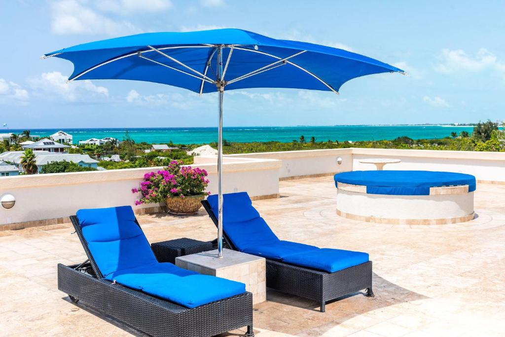 a pair of blue chairs and an umbrella on a patio at Sea Esta Studio III - Cozy for Couples! in Turtle Cove