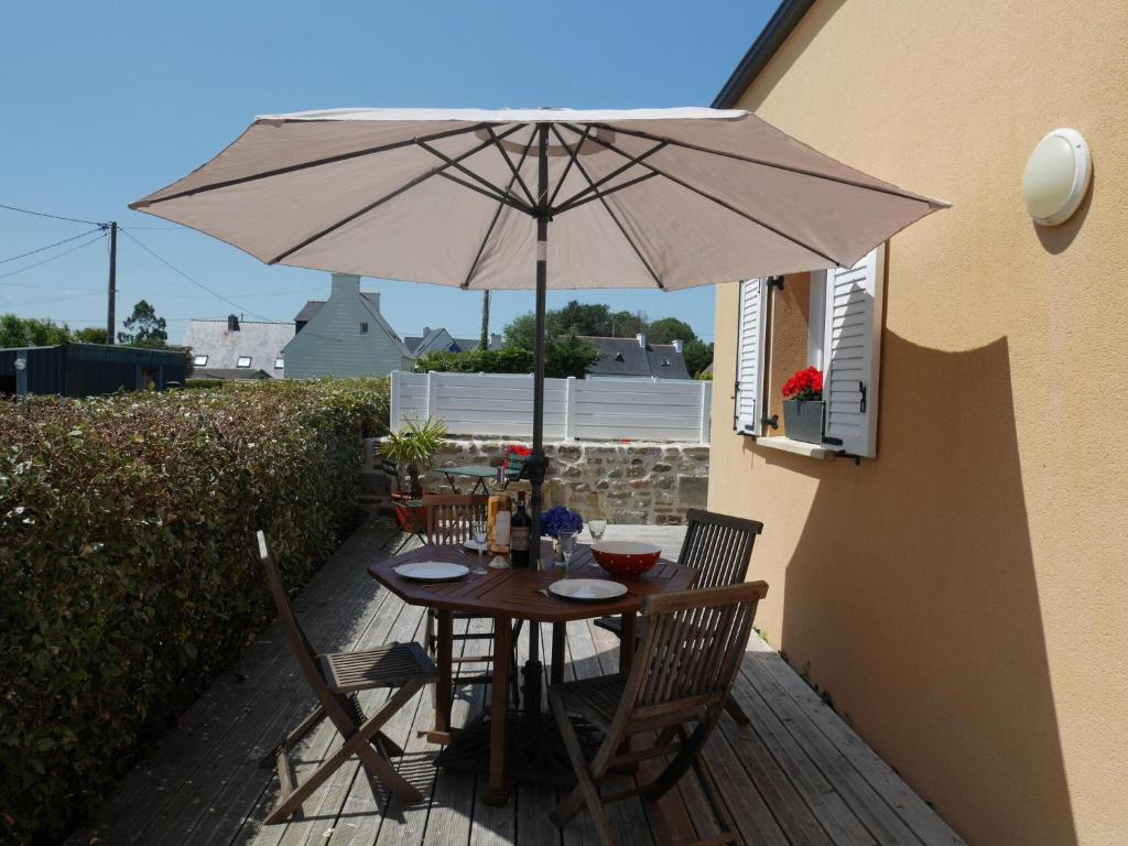 a table and chairs under an umbrella on a patio at Holiday home with sea views, Plounéour-Brignogan-Plages in Plounéour-Trez