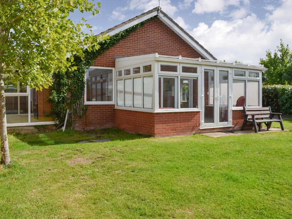 a house with a conservatory with a bench in the yard at Hollands Pond in Thorpe Saint Peter