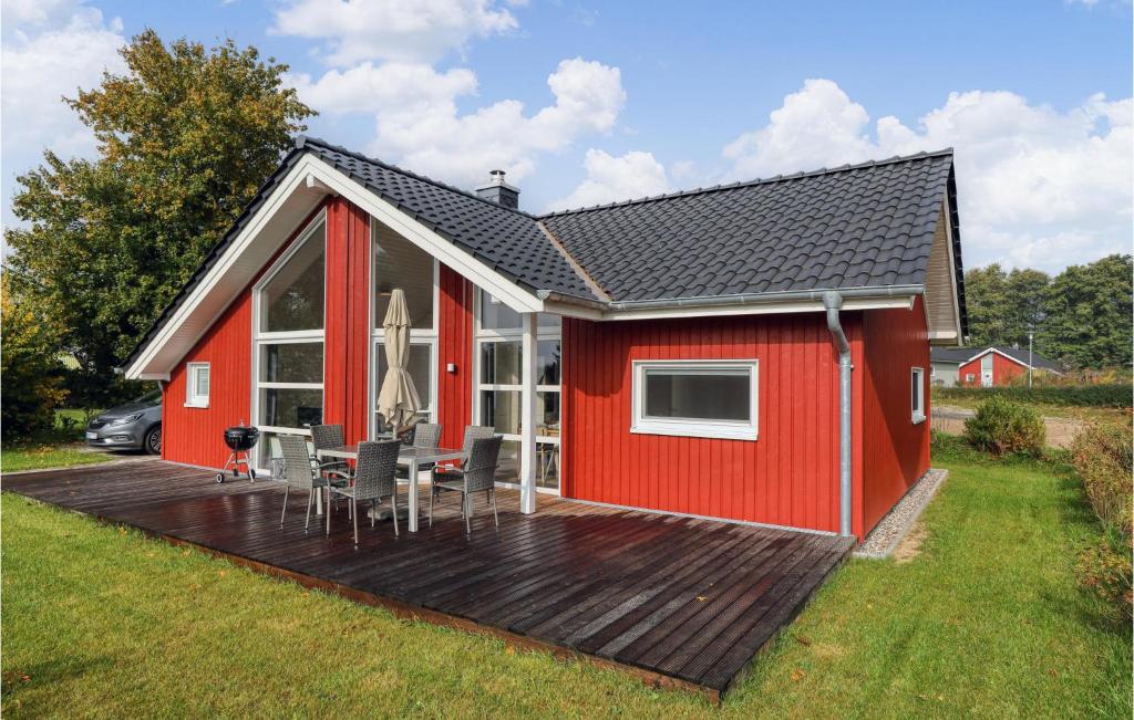 a red house with a deck with a table and chairs at Cozy Home In Krems Ii-warderbrck With Kitchen in Göls
