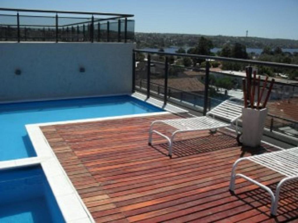 terraza con sillas y balcón con piscina en Village Tower en Villa Carlos Paz