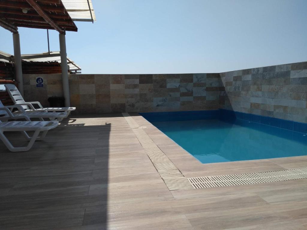 a swimming pool with two lounge chairs and a table at Acogedor departamento WiFi in Piura