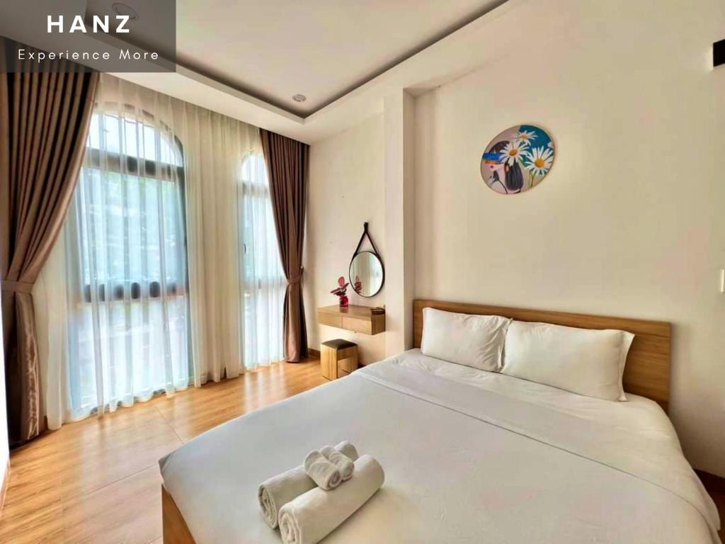 a bedroom with a white bed with a towel on it at HANZ Teddy Sunset Grand World in Phú Quốc