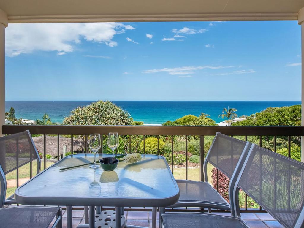una mesa y sillas en un balcón con vistas al océano en 23 Sunseeker, en Sunshine Beach