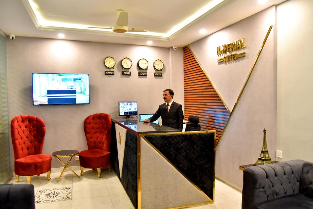 a man standing at a reception desk in a hotel lobby at Imperial Suites in Lahore