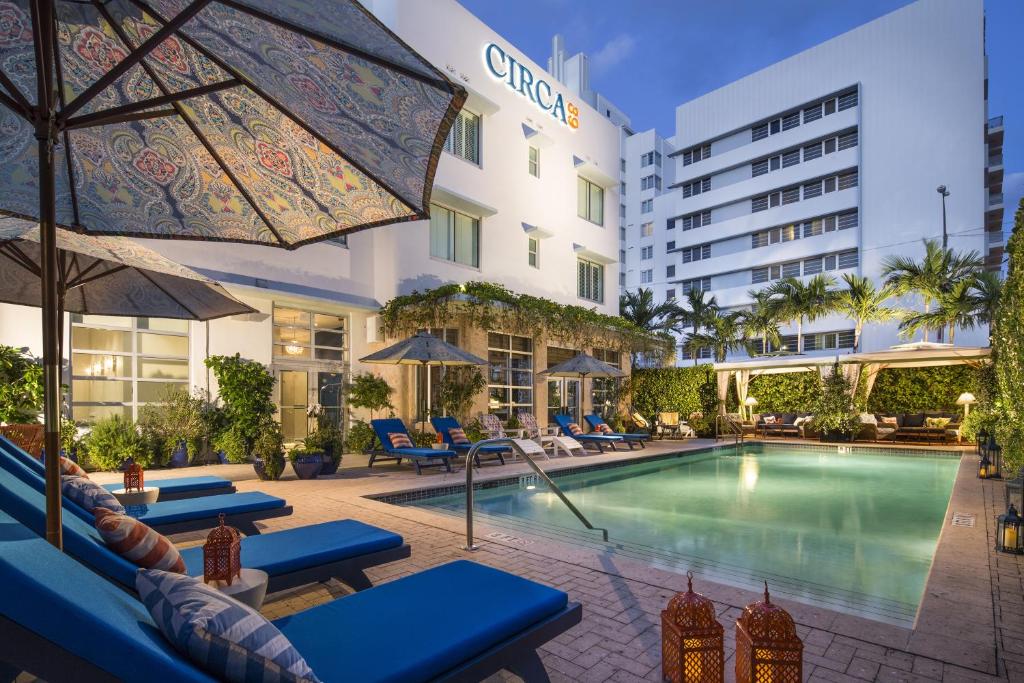 a hotel room with a pool, chairs, tables and umbrellas at Circa 39 Hotel Miami Beach in Miami Beach